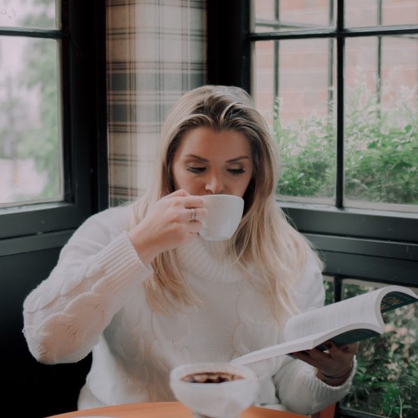 Woman drinking coffee while reading a book